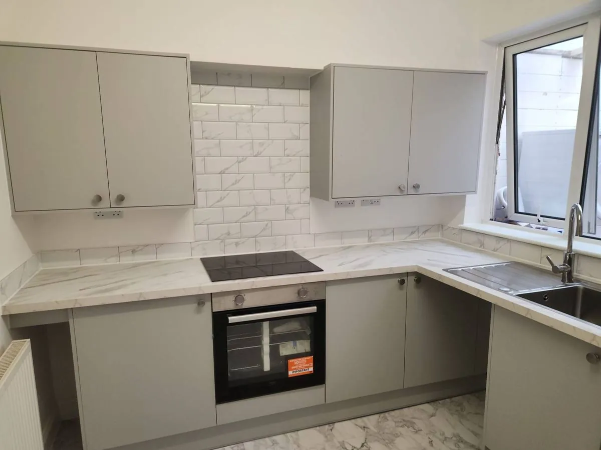 Kitchen fitting with grey units and marble-effect worktops